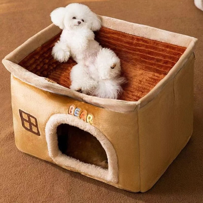 Petit chien blanc détendu, couché sur le toit amovible ouvert d’une niche pour chien marron style chalet, en tissu doux et moelleux. Disponible chez Museau Dort.