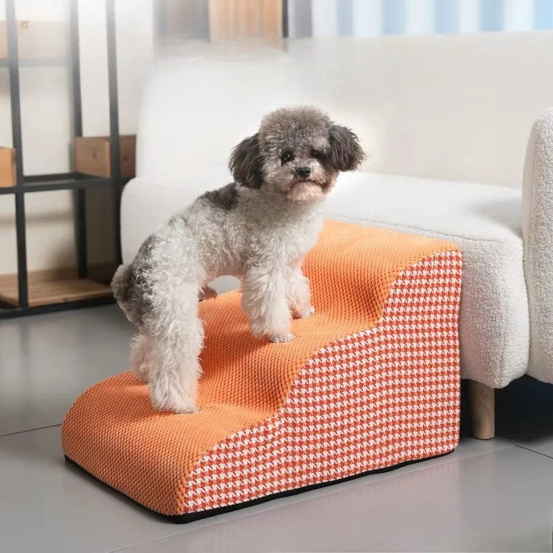 Petit chien assis sur un escalier pour chien orange Ă 3 marches, structure en mousse haute densitĂ© avec revĂȘtement antidĂ©rapant, idĂ©al pour accĂ©der au canapĂ©, disponible chez Museau Dort