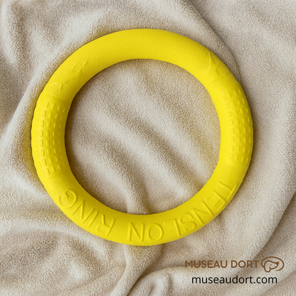 Anneau jaune pour jouet interactif pour chien posé sur une couverture beige douce, idéal pour les jeux de lancer