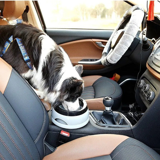 Chien buvant dans une gamelle anti-débordement posée sur la console centrale d'une voiture. Disponible chez Museau Dort.