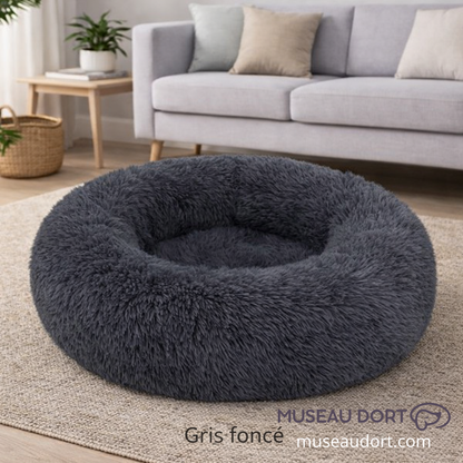 Coussin pour chien cocon gris foncé, moelleux et confortable, posé dans un salon moderne, idéal pour chien d’intérieur.