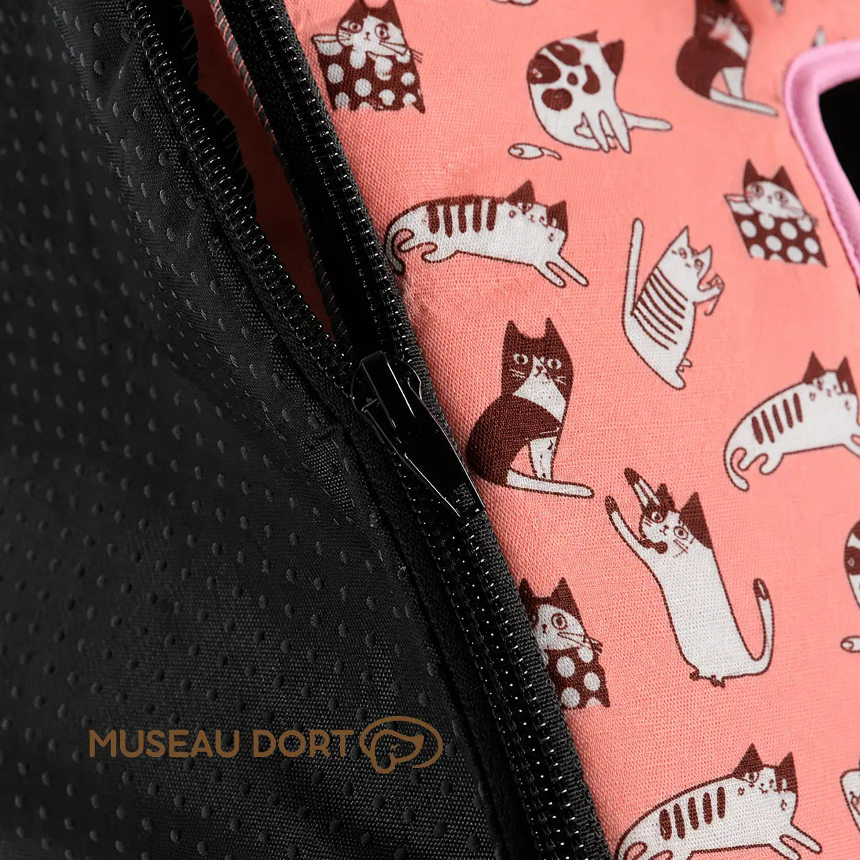 Détail de la fermeture éclair noire et du tissu rose à motifs chats de la maison pour chien pliable.
