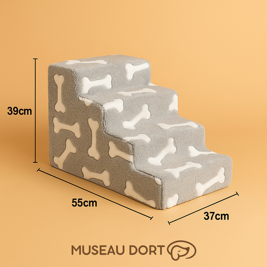 Escalier pour chien en mousse grise avec motifs os, dimensions 37x55x39 cm, fond beige – Disponible chez Museau Dort.

