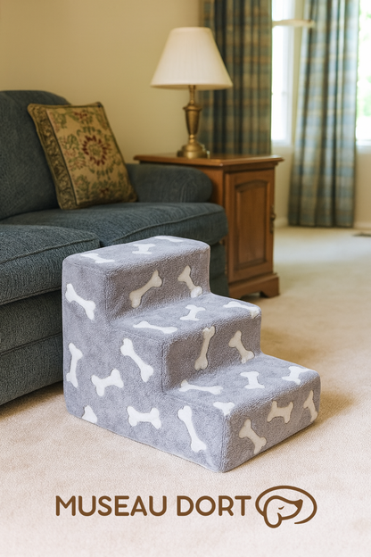 Escalier pour chien en mousse gris avec motifs os, placé dans un salon style début 2000 avec canapé bleu et lampe en laiton – Disponible chez Museau Dort