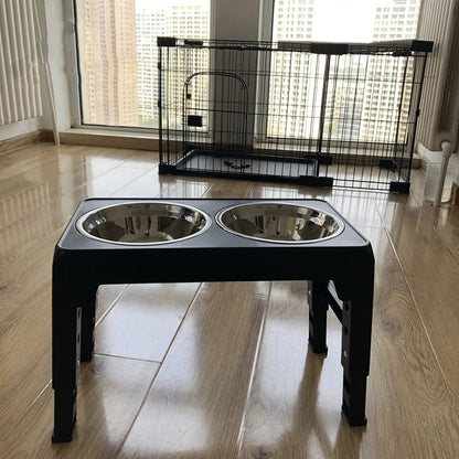 Gamelle surélevée noire avec deux bols inox posée devant une cage pour chien dans un appartement
