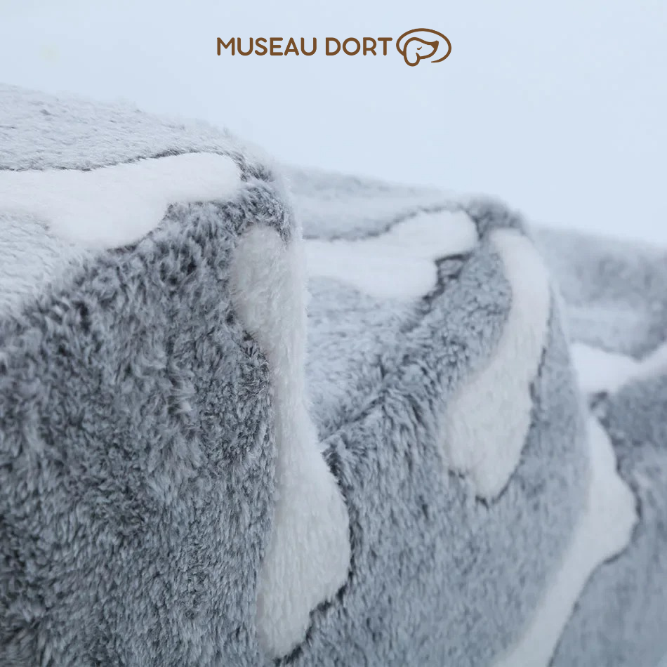  Gros plan sur la texture douce en peluche grise à motifs os blancs d’un escalier pour chien, logo Museau Dort en haut – Disponible chez Museau Dort
