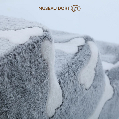  Gros plan sur la texture douce en peluche grise à motifs os blancs d’un escalier pour chien, logo Museau Dort en haut – Disponible chez Museau Dort