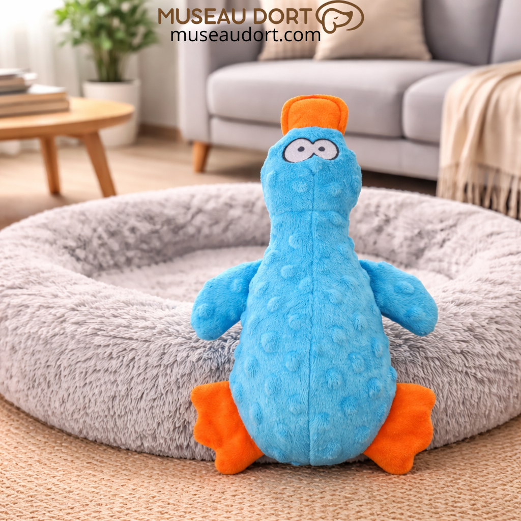 Jouet canard bleu pour chien sur lit gris, stimulant ludique et dentaire. Disponible chez Museau Dort.