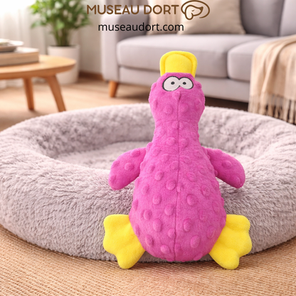 Jouet canard rose fuchsia pour chien sur lit gris, stimulant ludique et dentaire. Disponible chez Museau Dort.