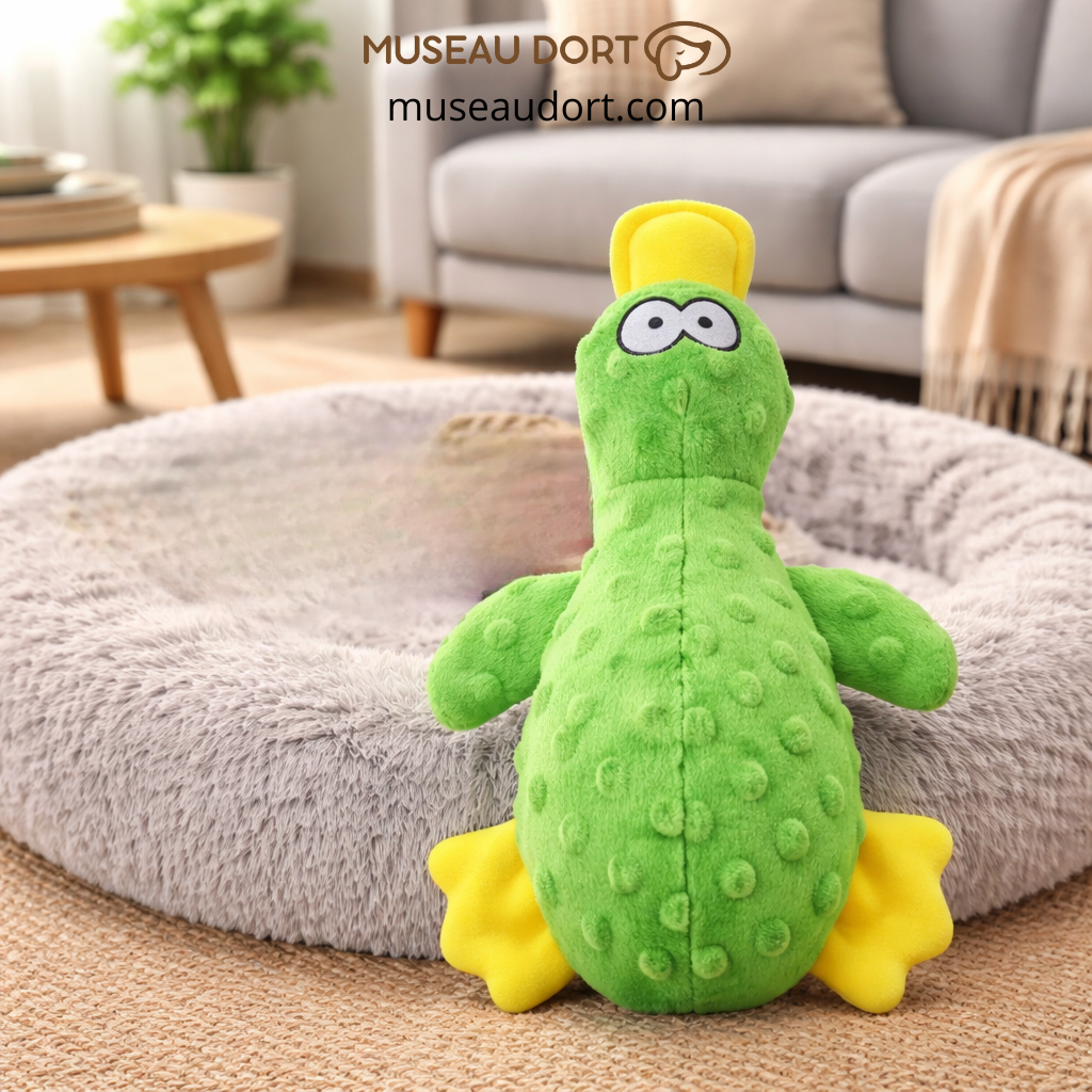 Jouet canard vert pour chien sur lit gris, stimulant ludique et dentaire. Disponible chez Museau Dort.