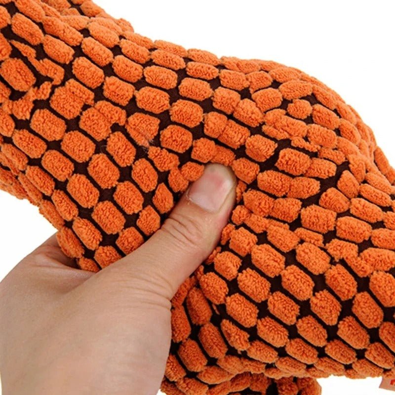 Zoom sur la texture résistante de la peluche dinosaure pour chien, montrant sa capacité à supporter la pression.
