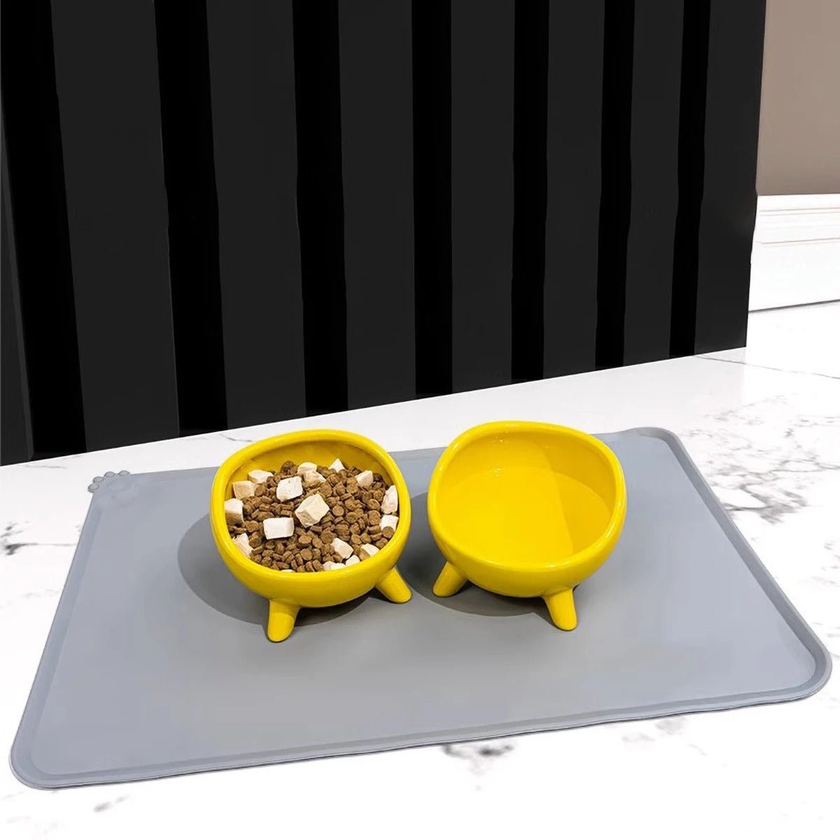 Gamelles jaunes posées sur un tapis gamelle chien gris en silicone antidérapant avec croquettes et eau Museau Dort
