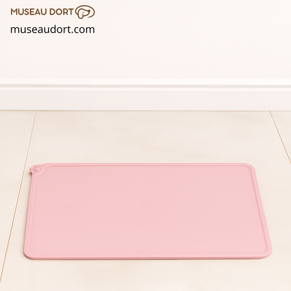Tapis gamelle chien rose en silicone  posé sur un sol carrelé clair devant un mur blanc, décor neutre Museau Dort