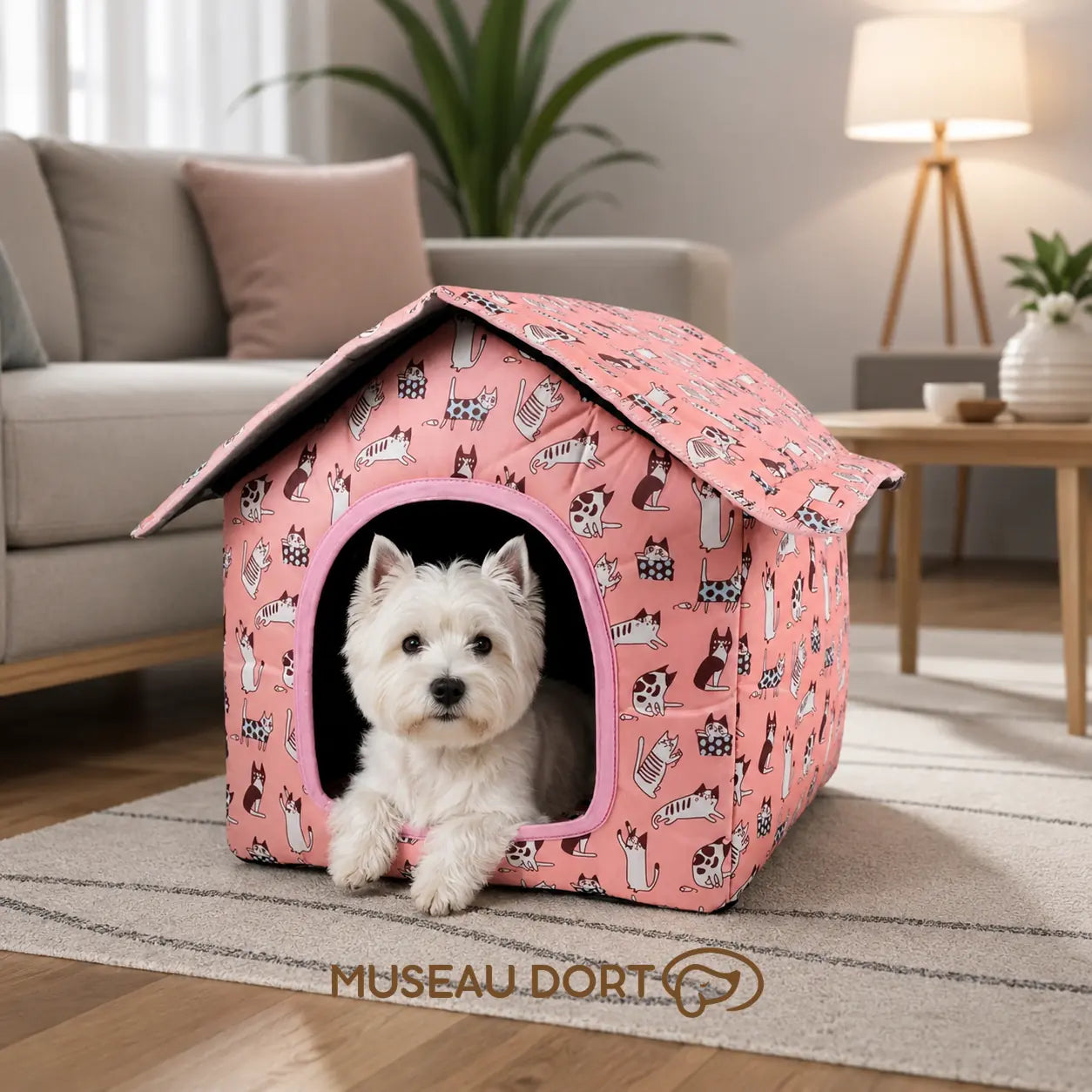 Petit Westie installé dans une maison pour chien rose à motifs chats, au cœur d’un salon moderne et lumineux.